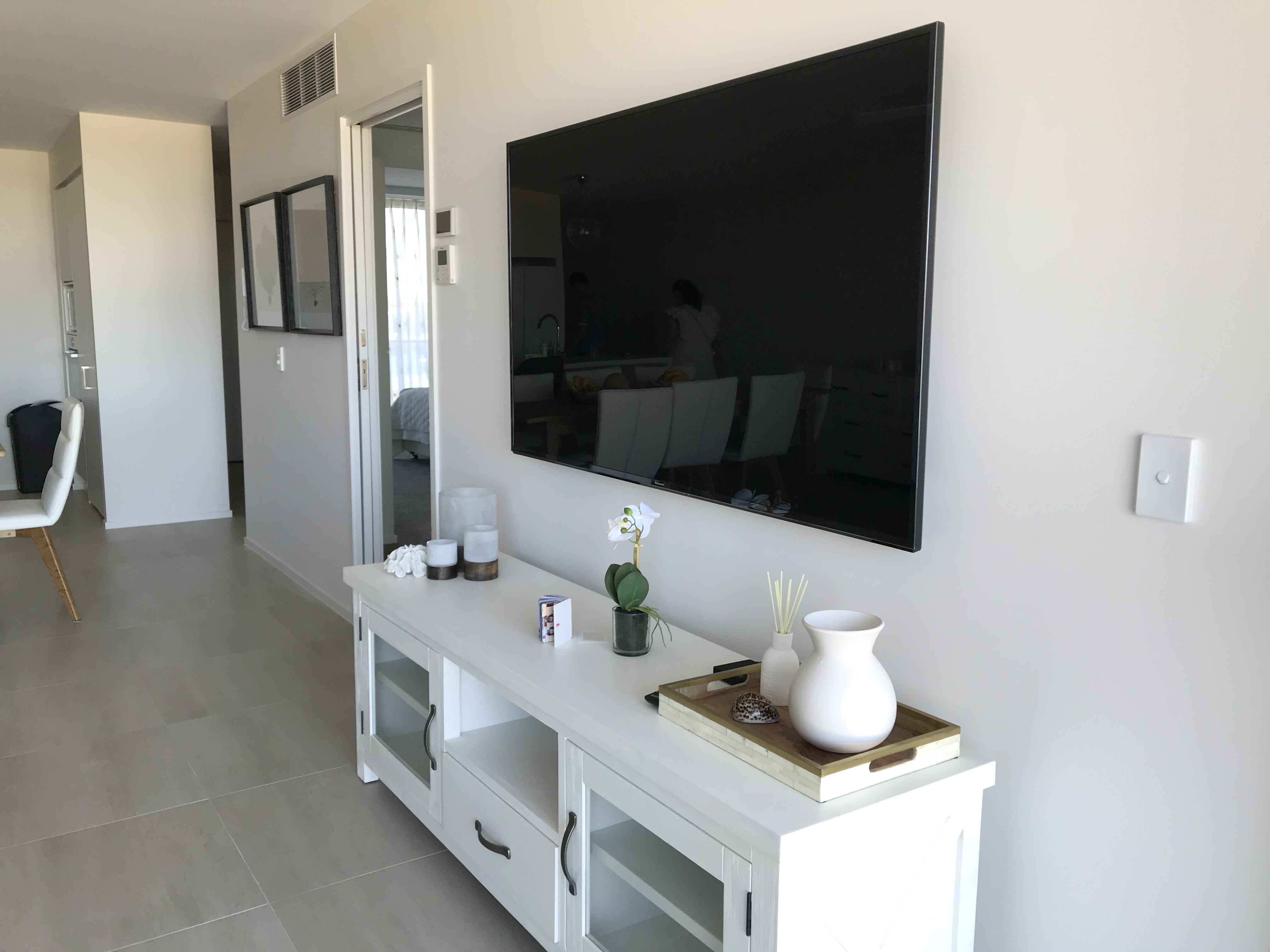 TV mounted in styled apartment above white sideboard