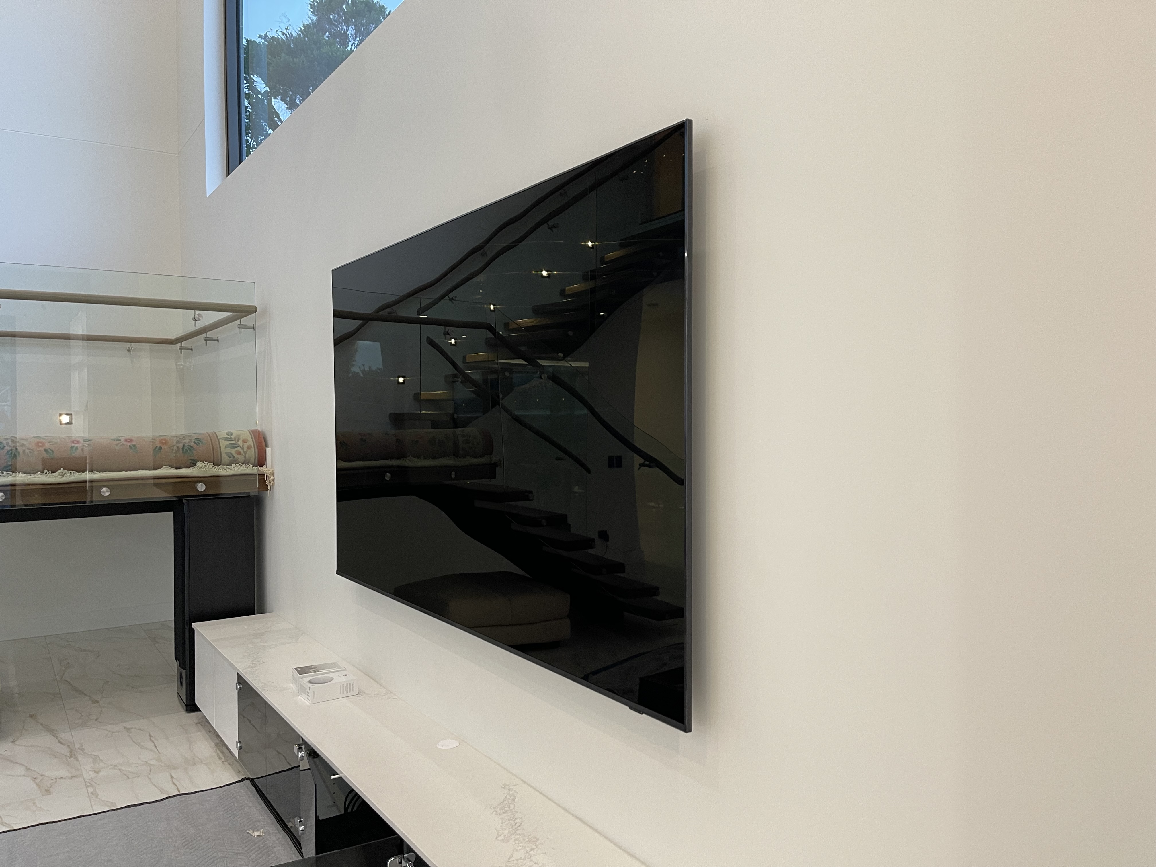 Large frameless TV in luxury home with floating staircase