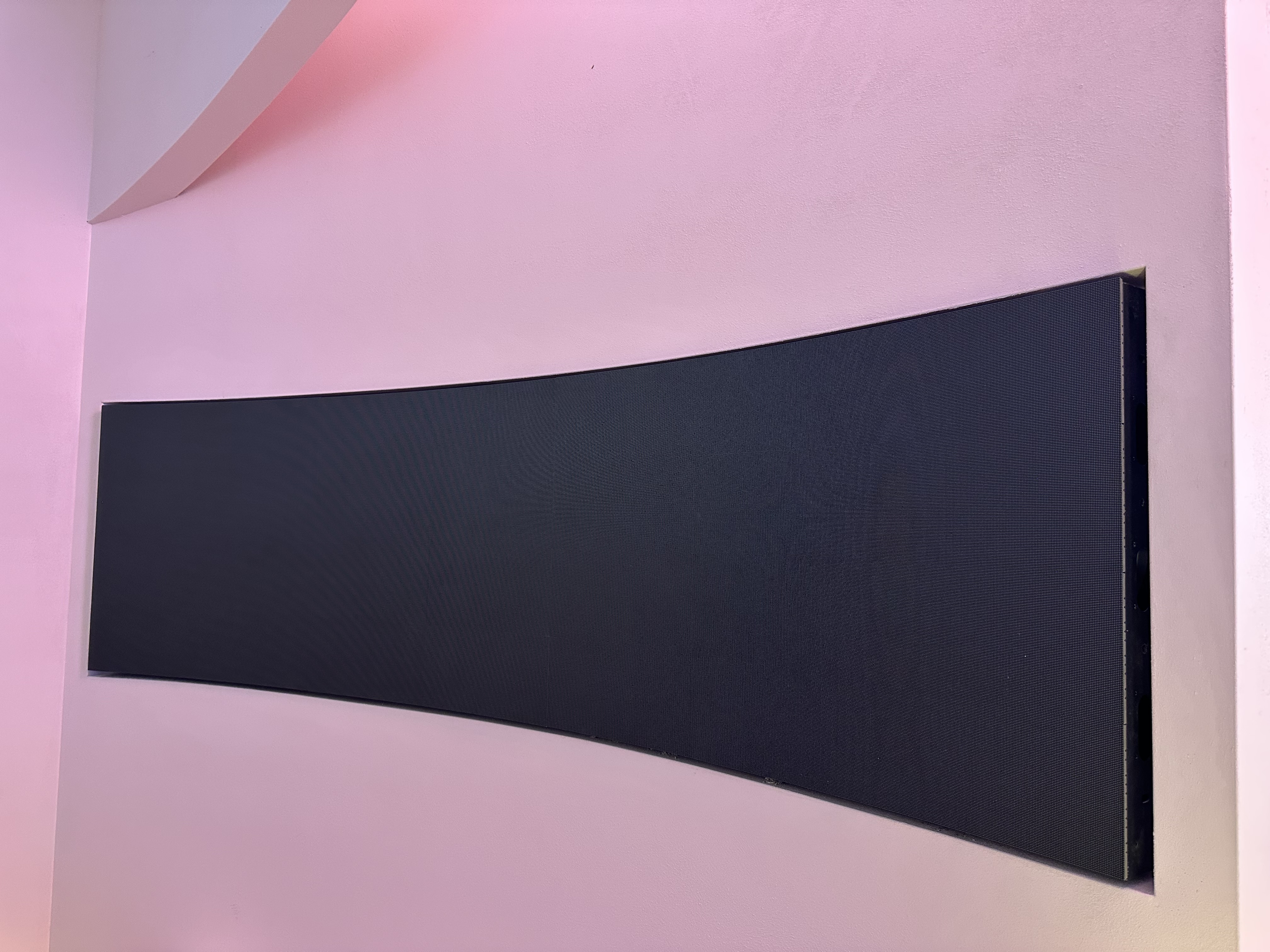 Curved LED panel recessed into pink feature wall