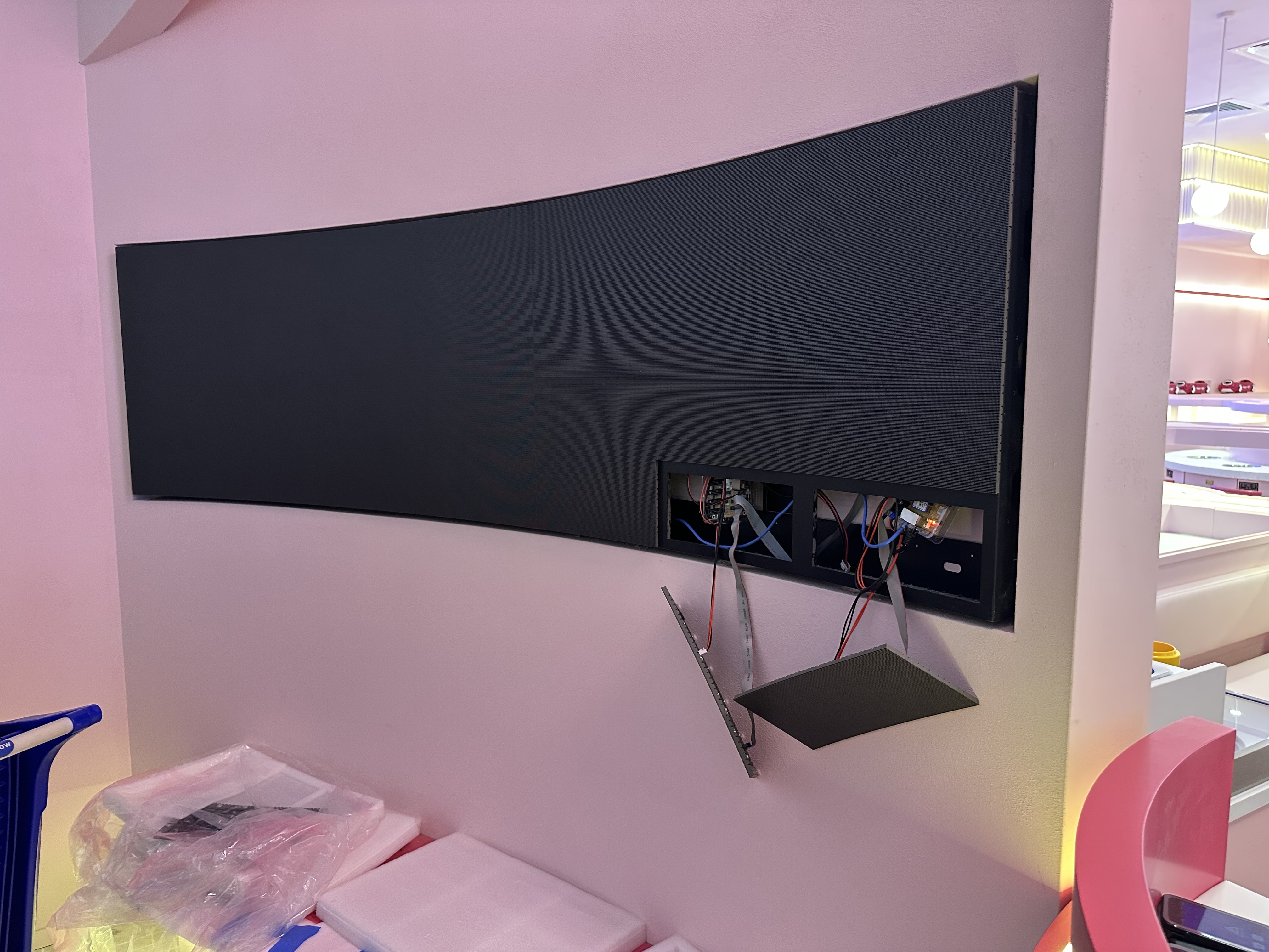 Curved LED panel installation in progress, pink retail store