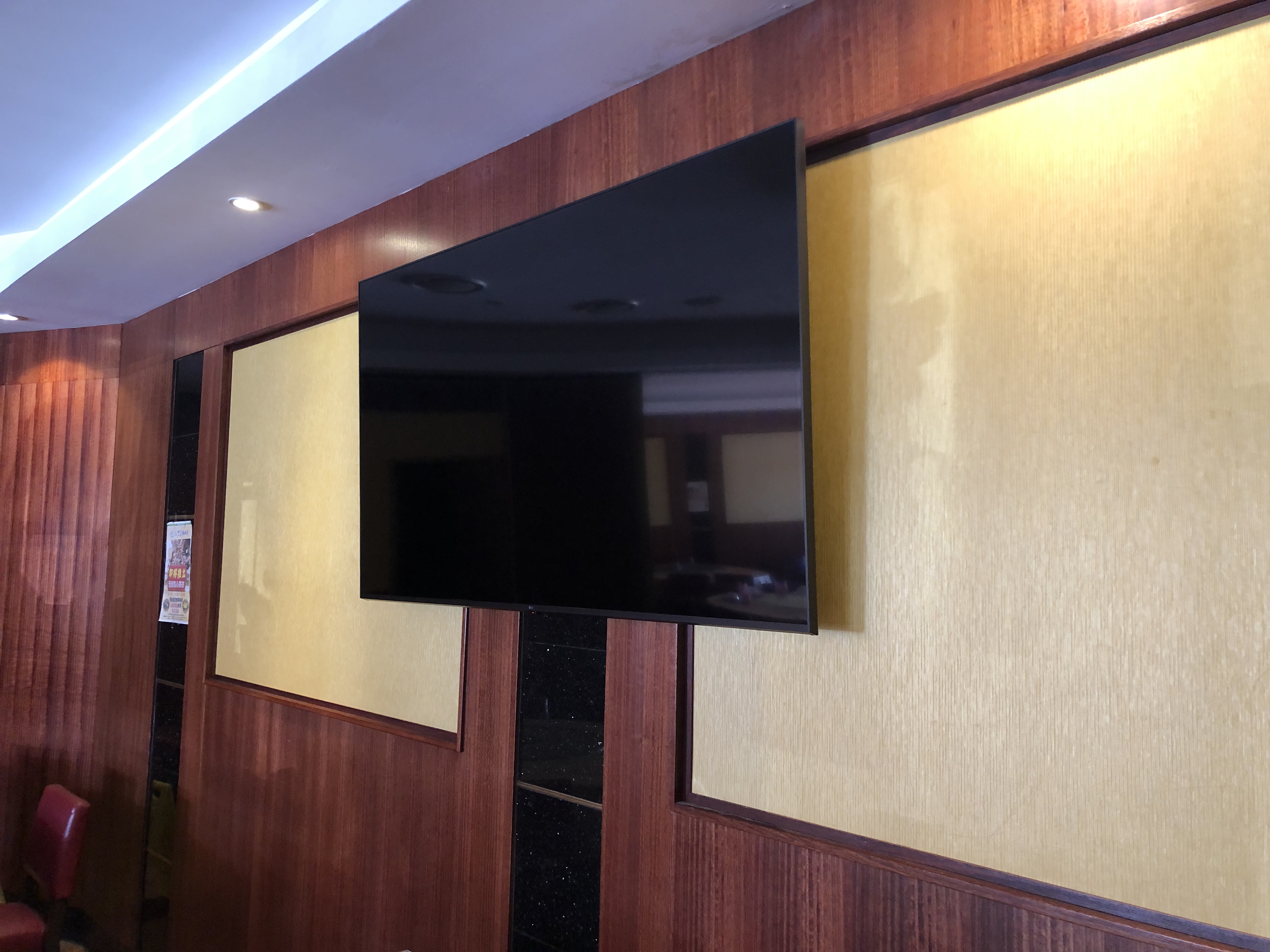 Large TV on decorative timber panelled restaurant wall